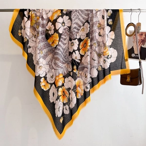 Close-up of floral print silk scarf with fringed edges and yellow border detail