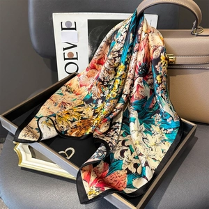 Luxury floral silk square scarf with vibrant botanical print draped on a leather handbag