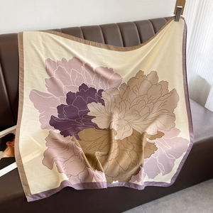 Elegant large floral print square scarf draped on a leather sofa as a stylish shawl