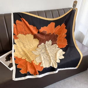 Detail of floral square scarf with large orange petals on black fabric draped on leather