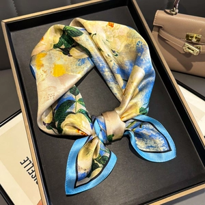 Elegant floral silk square scarf in yellow and blue, tied as a stylish necktie on a tray