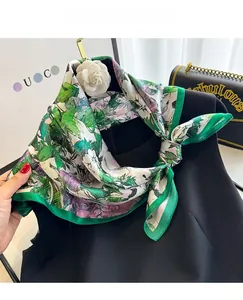 Detail of 100% mulberry silk floral scarf with camellia brooch on black dress