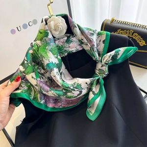 Detail of floral silk scarf tied elegantly on a neck with dark green border accents