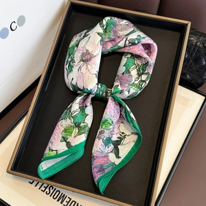 Floral print silk scarf with pink and green patterns on an elegant display tray