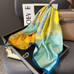 Elegant silk scarf with abstract lake blue and yellow print draped on a display tray