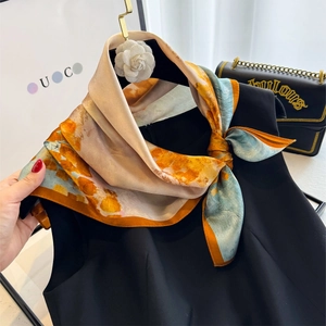 Artistic silk square scarf with vibrant orange and blue abstract prints on a black top