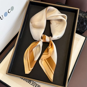 Detail of elegant champagne silk scarf with geometric border and smooth satin texture