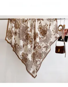 Close-up of vintage brown floral patterns on creamy white scarf with fringe edges