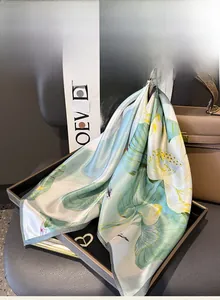Mulberry silk scarf with lotus print tied to a handbag as an elegant accessory detail