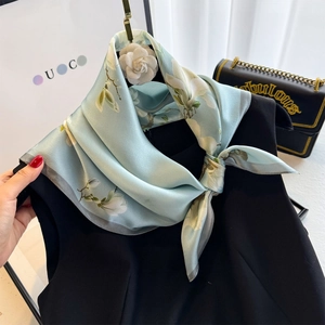 Detail of silk scarf with lotus print worn on a black dress in an elegant setting
