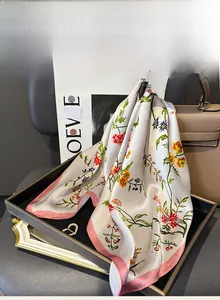 Détail du foulard carré en soie de mûrier à imprimé fleuri et ourlet rose sur sac en cuir