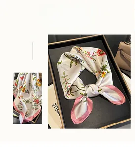 Détail d'un foulard en soie montrant des imprimés floraux et des bords ourlés en rose