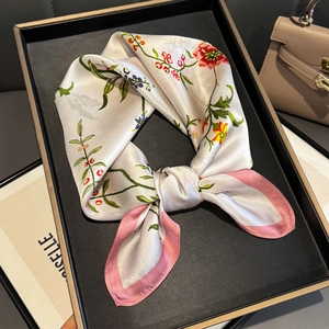 Détail d'un foulard en soie à fleurs ivoire avec bordure rose dans un coffret cadeau noir