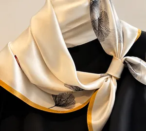 Dettaglio di un foulard in seta con foglie di ginkgo e bordo rifinito in oro
