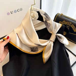 Dettaglio foulard in seta con motivo ginkgo e bordo giallo su top nero senza maniche