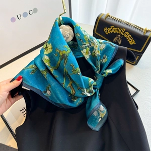Detail of blue silk scarf featuring Van Gogh almond blossom print tied on a black top