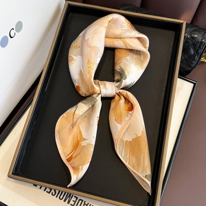 Detail of oil painting print silk scarf tied in a tray with warm orange and beige tones