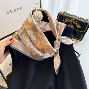 Detailed view of floral silk scarf styled with a knot on a black dress and accessory
