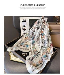 Detailed view of a silk scarf with floral and crane patterns on a designer tray