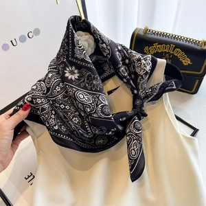 Elegant vintage black and white silk scarf with paisley pattern tied on a chic outfit