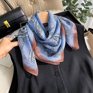 Blue paisley silk-like chiffon scarf tied elegantly on a minimalist black vest