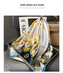 Detail of silk scarf with artistic ink splash and floral pattern on leather handbag