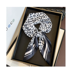 Detail of leopard print silk scarf tied in a bow on a black display tray with golden trim