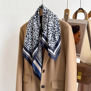 Fashionable leopard print silk scarf with chain pattern styled on a camel blazer jacket