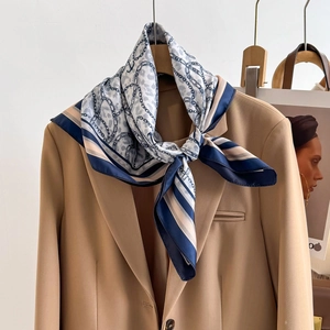 Elegant silk scarf with leopard print and chain patterns on a camel blazer