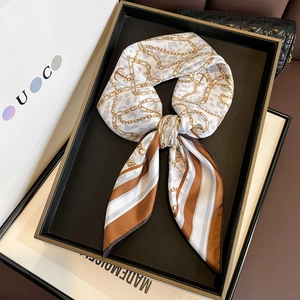 Luxurious leopard print silk scarf with golden chain pattern tied in an elegant bow