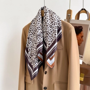 Detail of silk scarf with leopard print and stripe border styled on a brown blazer
