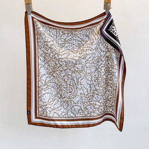Detail of leopard print silk scarf featuring golden chains and anchor patterns