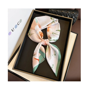 Detail of floral silk scarf in orange pink with butterfly print and green hemline