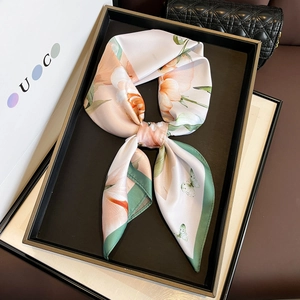 Elegant silk scarf with floral butterfly print shown on luxury bag background