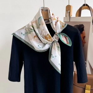 Elegant floral square scarf with butterfly print tied over a black sweater on a hanger