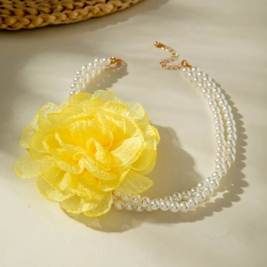 Close-up of double-layer pearl necklace featuring a large yellow chiffon flower detail