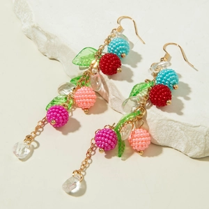 Detail of handmade bohemian earrings with colorful beaded spheres and green leaves