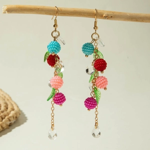 Floral tassel drop earrings with matte berries and green leaves on wood branch
