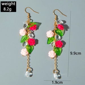 Detail of pink resin rose tassel earrings with green leaves and crystal charms