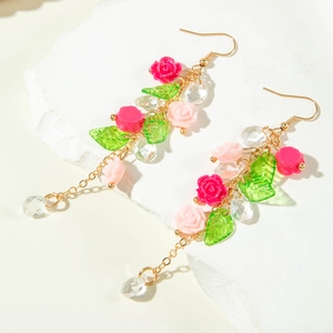 Detailed macro view of long floral tassel earrings with resin roses and green leaves