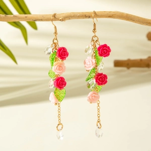 Detailed shot of floral tassel earrings with rose petals on a natural wood branch