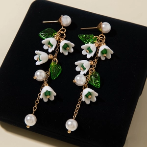 Detail of lily of the valley earrings with white resin flowers and gold metal chains