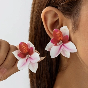 Detail van grote orchideeënoorbellen in boho-stijl met roze en wit kleurverloop