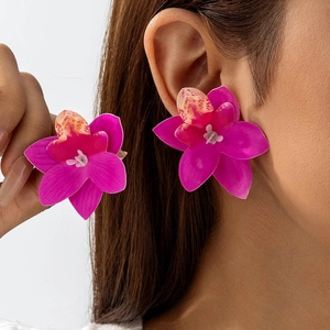 Detail van een grote magenta orchidee oorbel met natuurlijke gespikkelde textuur op model
