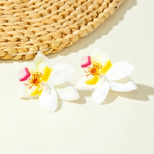 Detail van bohemien witte orchidee oorbellen met levendige gele en roze accenten
