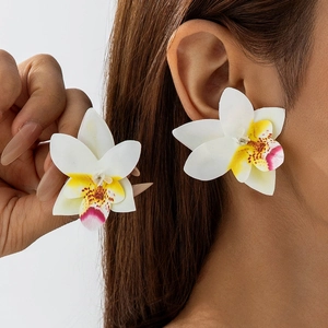 Gedetailleerde close-up van 3D orchidee oorbellen met witte bloemblaadjes en geel hart