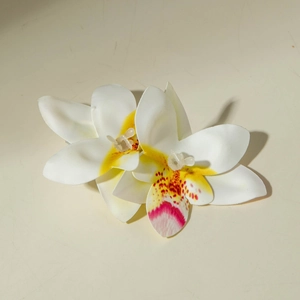 Detailopname van witte orchidee haarspelden met stoffen bloemblaadjes en geel hart