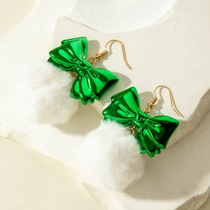 Detail of green bow earrings with white fluffy pom pom on white decorative stone