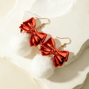 Close-up of festive red bow earrings with white fluffy pom-poms on stone background