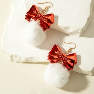 Detail of red bow earrings with white fuzzy pom poms and golden metal hooks